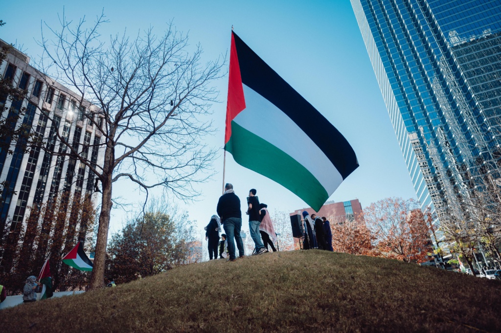 People in city with person holding large Palestinian flag